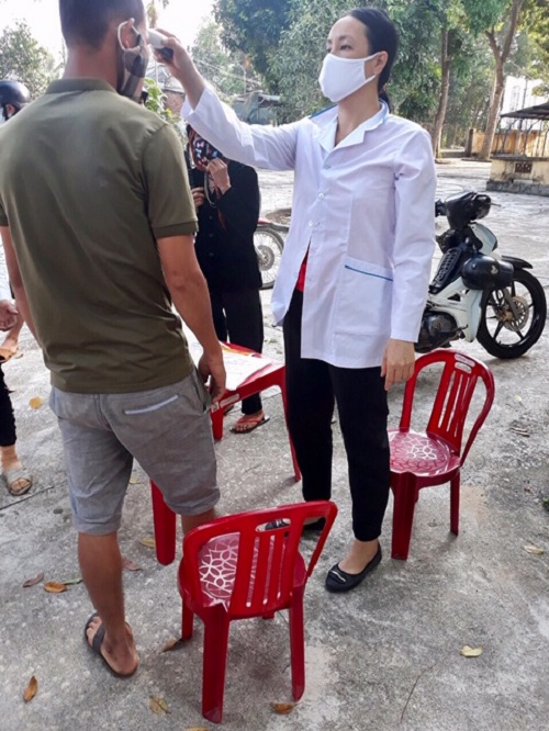 Nhân viên Y tế đo thân nhiệt cho người dân đến khám bệnh tại Trạm y tế
